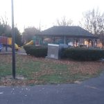 Park scene with playground equipment and a gazebo under an overcast sky.