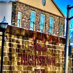 Stone building with "Hightstown" sign, featuring multiple windows under a clear blue sky.