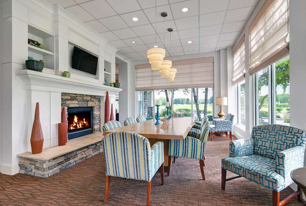 Modern dining room with stone fireplace, large windows, and light wood table.