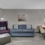 Modern waiting area with gray patterned wallpaper, blue sofa, and desk setup.