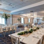 Elegant ballroom set for a formal event with long dining tables and chandeliers.