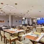 Modern, bright restaurant interior with dining tables and a bar area.