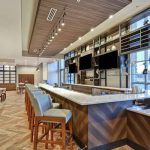 Modern bar area with wood ceiling, wine display, and seating in a contemporary restaurant.