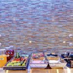 Mosaic tile wall backdrop with a buffet display featuring food platters and chafing dishes.