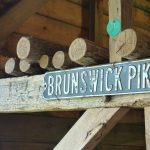"Brunswick Pike" sign mounted on rustic wooden beams and logs.