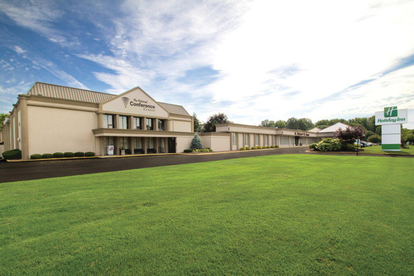 Hotel and conference center building with expansive green lawn under a blue sky.