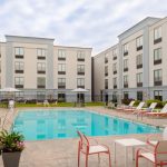Modern apartment complex with a sunny outdoor swimming pool and lounge area.