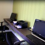Office desk setup with computer, printer, and ergonomic chair against a patterned wall.