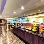 Hotel buffet display case with pastries and fruit, modern interior.