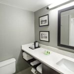 Modern bathroom vanity with white countertop, sink, and large mirror.