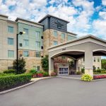 Modern hotel building entrance with covered porte-cochere under a blue sky.