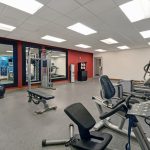 Gym interior with cardio machines, weight equipment, and mirrored walls.