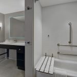 Modern bathroom with white tub, gray vanity, and minimalist design.