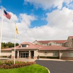 Hotel exterior with American flag flying under a partly cloudy blue sky.