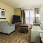 Hotel room interior with armchair, sofa, TV, and window view.