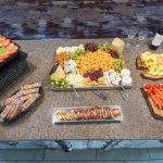 Charcuterie and cheese spread buffet with fruit, crackers, meats, and bread on a counter.