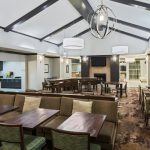 Modern, spacious dining area with high ceilings, dark wood tables, and comfortable seating.