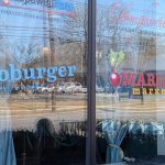 Storefront windows displaying "Hopewell Fare" and "Daugherty Artisanal Provisions" with outdoor view.