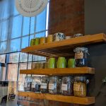Rustic bakery display with "Sourland Bread" sign, wooden shelves holding jars of grains and nuts.