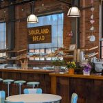 Rustic bakery interior with exposed brick, wooden counters, and sourdough bread display.