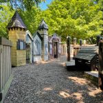 Fantasy castle playhouse in a sunny, wooded backyard setting with gravel ground.