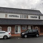Historic Hopewell Theater building with black roof, parked car in front.