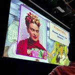 Large screen display featuring Frida Kahlo portrait and "Dreams, Demons, and Devotion" text.