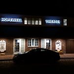 Night shot of Hopewell Theater facade with cars parked in front.