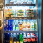 Refrigerated display case stocked with drinks, snacks, and desserts for self-service.
