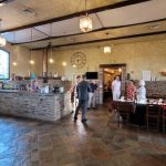 Rustic bar and dining area with exposed beams, stone counter, and warm lighting.