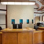 Modern cafe counter with warm wood, textured wall, and display case.