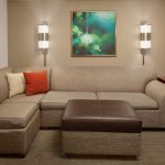 Sectional sofa in a living room with modern art and wall sconces.