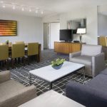 Modern hotel suite with dining area, living room, and kitchenette.