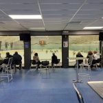 Indoor rink viewing area with seating overlooking an ice hockey rink during a game.