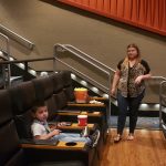 Woman and boy in a movie theater aisle with tiered seating.