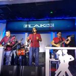 Band performing live on stage under a large "FLAKO" banner with blue lighting.