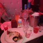 People socializing at a bar with drinks, snacks, and seating visible.