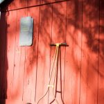 Red barn wall with a small chalkboard and an old, rustic metal cart.