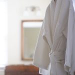 White terry cloth bathrobe hanging on a hook in a bright, modern bathroom setting.