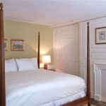 Elegant bedroom with a four-poster bed, light green walls, and white fireplace.