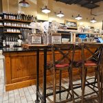 Rustic bar area with wooden stools, shelves of bottles, and a warm interior ambiance.