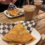 Savory quesadilla and iced coffee on a rustic wooden table.