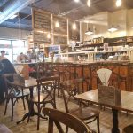 Cozy cafe interior with wooden tables, bar area, and menu boards.