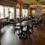 Warm, rustic restaurant interior with dark wood floors and dining tables.