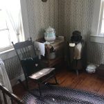 Vintage nursery room with patterned wallpaper, rocking chair, and antique furniture.