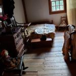 Rustic bedroom with wooden floors, a bed, and natural light from a window.