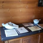 Wooden interior with a dark counter holding white ceramic and stacked papers.
