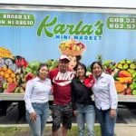 Family stands in front of Karla's Mini Market, a storefront with produce display.