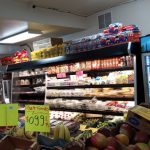 Grocery store aisle stocked with snacks, drinks, and fresh produce.