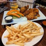 Fried chicken and fries served on white plates at a dimly lit restaurant.